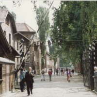 At the Gates to Hell.
Pictured at the entrance gates to Auschwitz are Romuald (far right), and Journalist Malcolm R Fane seen walking (far left).